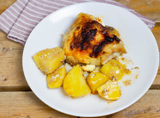 Chicken and potatoes on a white plate with a napkin. View from above.