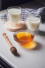 Milk and honey. Two glass glasses with milk and a bowl of honey on the table. Spoon for honey. Breakfast, snack. Calming and healthy drink.
