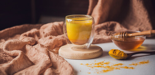 Turmeric latte, Cooking Golden Milk On Kitchen. Hot healthy drink. Milk, turmeric, honey. Banner