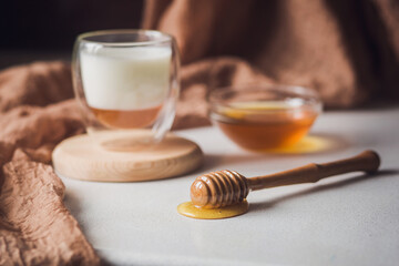 Milk and honey. Glass cup with milk and bowl with honey on the table. Spoon for honey. Breakfast, snack. Calming and healthy drink.