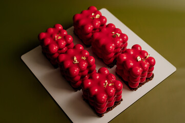 Beautiful mousse cakes covered with mirror shiny glaze. Green back ground. The skill of the pastry...