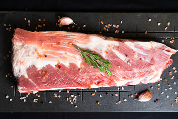 raw meat on a black board with chili, papper , garlic and rosemary