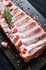 Raw ribs with rosemary on a black board