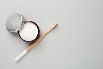 Jar of tooth powder and brush on light grey background, flat lay. Space for text