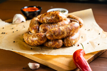 Sausages on a wooden and paper board with garlic and chili pepper