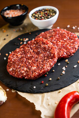 minced meat on a black round board with pepper and salt