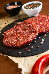 minced meat on a black round board with pepper, garlic  and salt