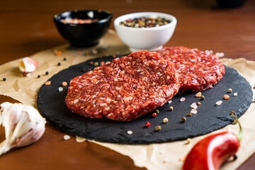 minced meat on a black round board with pepper, garlic and salt