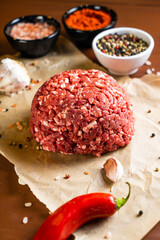 minced meat on a paper board with salt, garlic, pepper and paprika