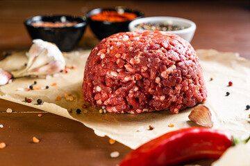 minced meat on a paper board with salt, garlic, pepper and paprika
