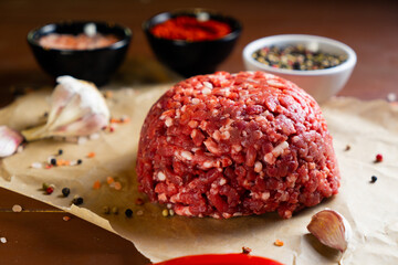 minced meat on a paper board with salt, garlic, pepper and paprika