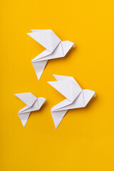 White origami doves as a symbol of faith, hope and peace on a yellow background - obrazy, fototapety, plakaty