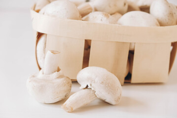 Fototapeta na wymiar Champignon mushrooms in a wicker basket on a white background