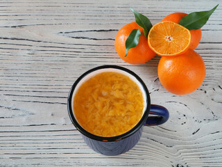 Natural fresh juice in a blue mug, tangerine, leaves on a white wooden table, top view, flat layout. Citrus reticulate healthy fruits with vitamin c for vegetarian and dietary nutrition