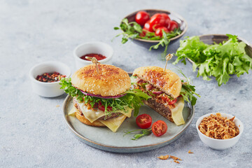 Two burgers with veal cutlet and herbs on wooden cutting board
