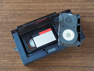 Mini compact videocassettes, videocassette adapter on a wooden table, flat layout, closeup. Retro...