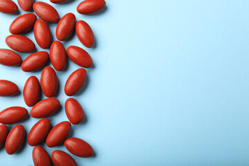 Red pills on light blue background, flat lay with space for text. Anemia treatment
