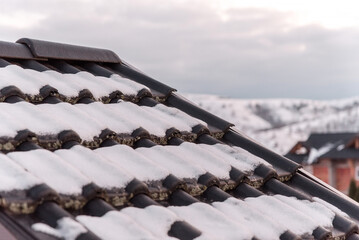 Dark snow covered beaver tail roof in dew weather