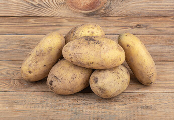 Ripe unpeeled unwashed potatoes on a wooden surface.