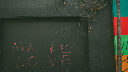Shoreditch, London, UK - April 14, 2016: Detail of some East London street art, with the words 'MAKE LOVE', inscribed on a doorway.