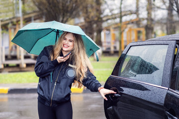 Happy young woman with umbrella getting in taxi car in rainy day - 498238485