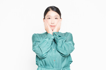 白背景の前で、頬に手を当てている主婦