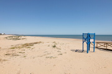 A blue wooden turret, indicating on a sign that dogs are prohibited on the beach of Isla Cristina, Spain during vacation times.