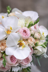 Wedding bouquet on gray stone background. Bridal bouquet composed of roses, freesia, peony and phalaenopsis orchids. Wedding day.