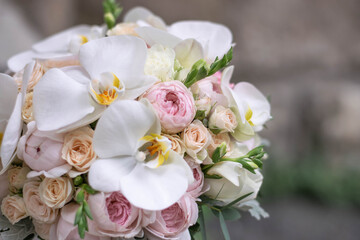 Wedding bouquet on gray stone background. Bridal bouquet composed of roses, freesia, peony and phalaenopsis orchids. Wedding day.
