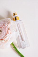 Bottle of perfume with rose flower on white background. Spring or summer floral fragrance. Top view, flat lay, close up, vertical