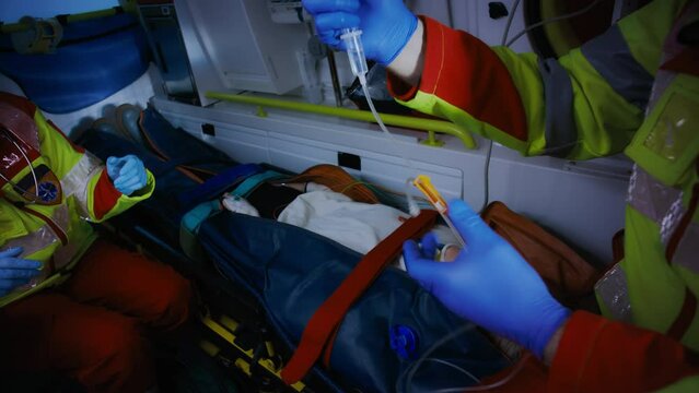 Close Up Shot of an Emergency Care Workers Hands As They Try and Connect an IV Drip To The  Patient Laying on a Stretcher Unconcious After Survivng a Bomb Attack.