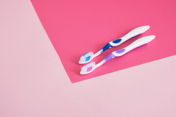 two toothbrushes on pink background copy space