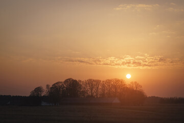 Fototapeta na wymiar Rural sunset over trees near a farm