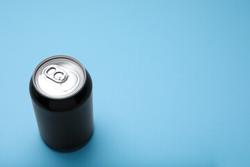 Black can of energy drink on light blue background. Space for text