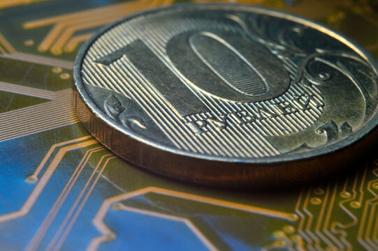 A coin with a face value of 10 rubles lies on a microcircuit. close-up. Translation of the inscription on the coin: "10 rubles" The concept of the digital economy in the Russian Federation