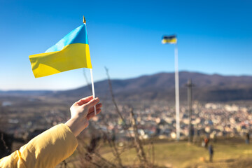 Flag of Ukraine in female hands against the sky.