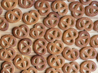 Pretzels sprinkled with sugar lie on a wooden surface