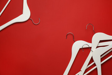 Empty clothes hangers on red background, flat lay. Space for text
