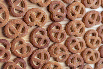 Pretzels sprinkled with sugar lie on a wooden surface