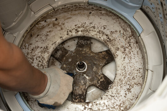 Man Taking Apart A Dirty Washing Machine