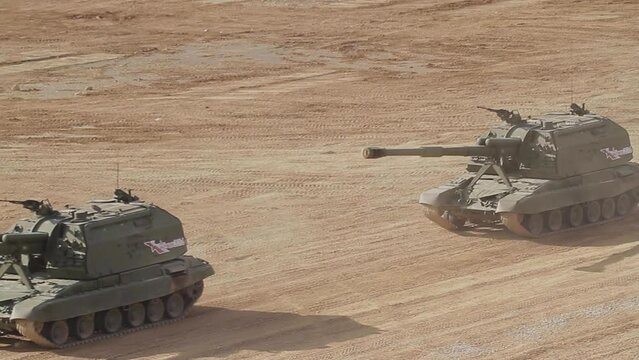 Two heavy Russian tanks are moving at high speed along the roads of the polygon.
