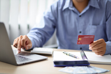 Fototapeta premium Businessman holding credit card and using laptop. Online shopping ideas and credit card balance check.