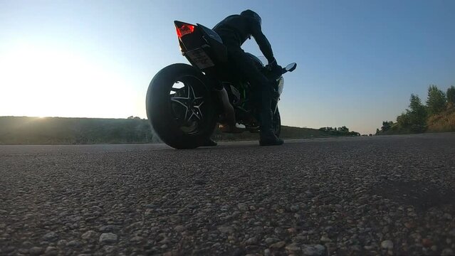 Biker performing tire burnout with lots of smoke. Wheel of sport motorbike starting to spin at asphalt road. Motorcycle starts the movement. Concept of stunts and lifestyle. Slow motion Close up