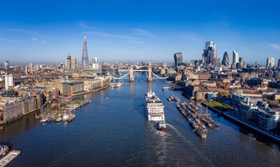 Fototapeta na wymiar Aerial view of the moder skyline of London with the lifted Tower Bridge and a cruise ship passing under during a sunny morning