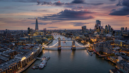 Aerial view of the illuminated Tower Bridge and London skyline during dusk