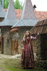 Fototapeta na wymiar Girl in medieval attire near the old castle.