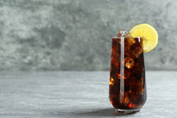 Glass of refreshing soda water with ice cubes and lemon slice on grey table, space for text