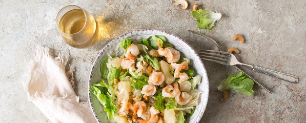 a bowl of salad with pomelo and shrimps on a light table