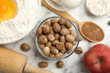 Nutmeg seeds and other ingredients for pastry on white marble table, flat lay