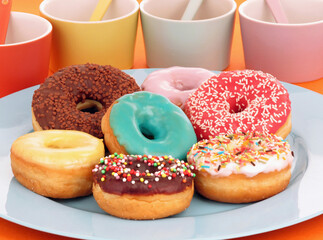 Variety of colorful donuts plate on party table background.